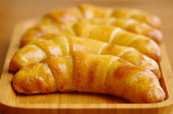 Deliziosi, freschi, croccanti e gustosi croissant al forno sul tavolo di legno — Foto Stock