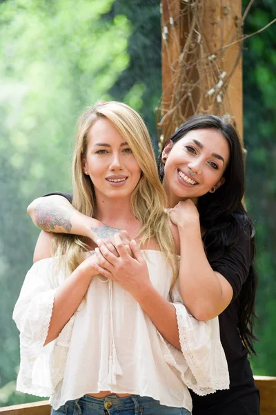 Um par de lésbicas orgulhosas ao ar livre olhando umas para as outras, em um fundo de jardim — Fotografia de Stock