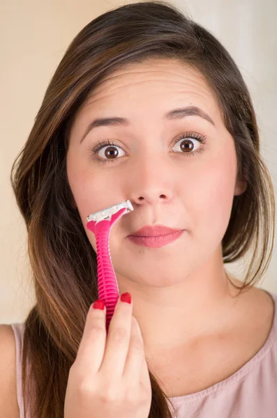 Close up de uma bela jovem mulher usando um barbeador fingindo raspar o bigode, em um fundo branco — Fotografia de Stock