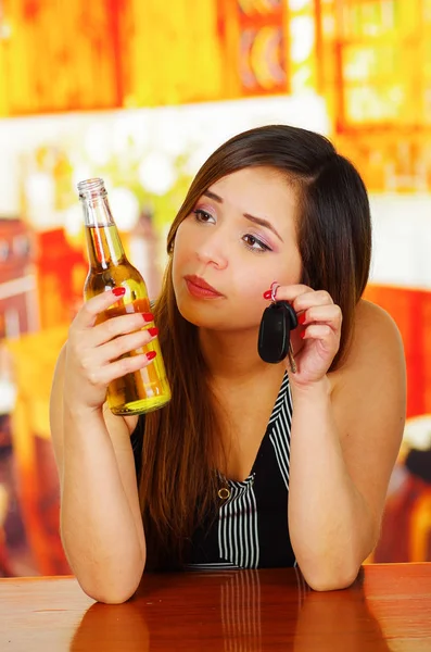 Retrato de una hermosa mujer mirando su cerveza y sosteniendo las llaves de su coche con la mano, en el fondo del bar — Foto de Stock