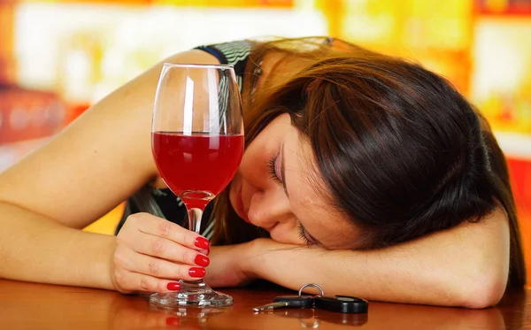 一个醉酒的女人睡在一张木桌，举着杯子，芦苇酒与她的手，在酒吧背景的肖像 — 图库照片