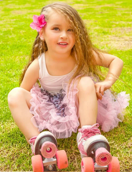 Little girl preschool beginner in roller skates, in a grass background — Stock Photo, Image