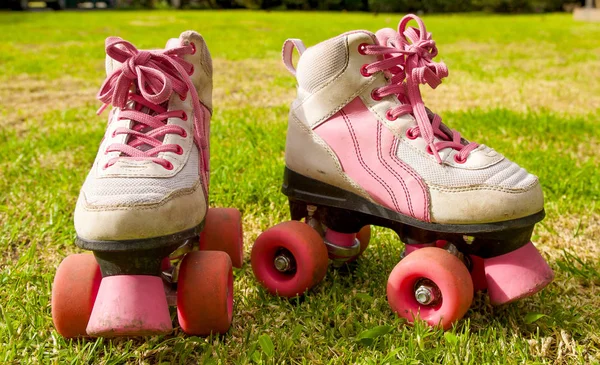 Mooie roze rolschaatsen op gras achtergrond — Stockfoto