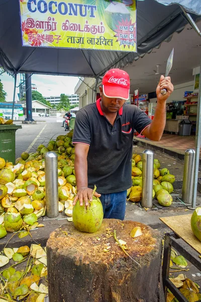Kuala Lumpur, Malasia - 9 de marzo de 2017: Vendedor ambulante desconocido corta y vende coco fresco a los turistas . —  Fotos de Stock