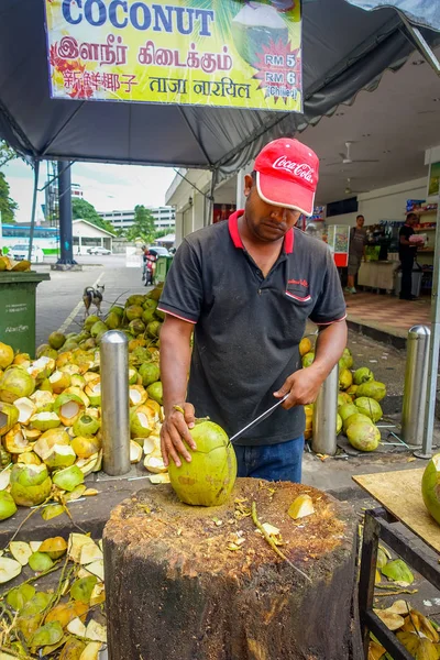 Kuala Lumpur, Malajzia - 2017. március 9.: Ismeretlen street szállító személy vágás és értékesítési friss kókusz, a turisták. — Stock Fotó