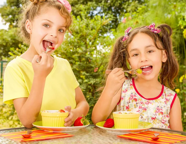Sağlıklı bir çilek ve Bahçe arka planda bir çatal kullanarak üzüm yemek iki güzel genç kızlar — Stok fotoğraf
