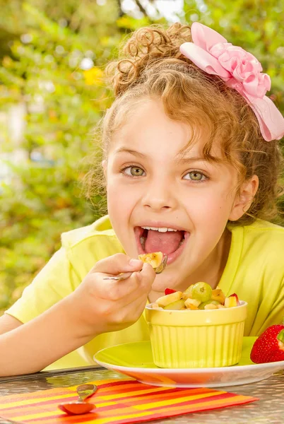 Güzel bir genç kız, bir bahçe arka planda bir çatal kullanarak sağlıklı bir muz yemek — Stok fotoğraf