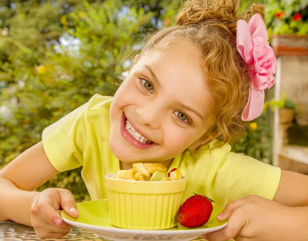 Close up van een mooi jong meisje met een geel t-shirt, voorbereiden om te eten een gezonde fruitsalade in een tuin achtergrond — Stockfoto