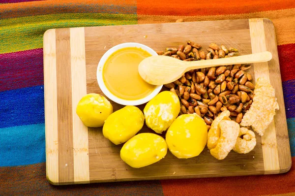 Plato tradicional ecuatoriano, papas, tostados y tazón de salsa con cuchara de madera, visto desde arriba — Foto de Stock