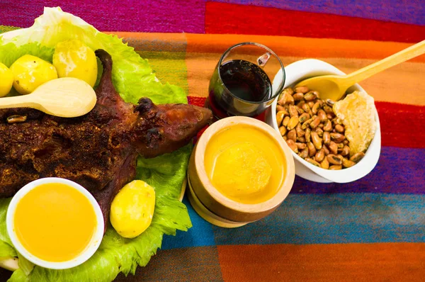 Traditional ecuadorian dish, grilled guinea pig spread out onto green plate, potatoes, tostados and lemons on the side, seen from above — Stock Photo, Image