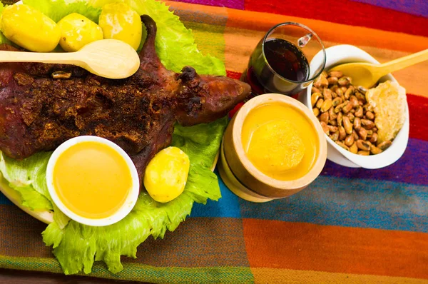 Traditional ecuadorian dish, grilled guinea pig spread out onto green plate, potatoes, tostados and lemons on the side, seen from above — Stock Photo, Image