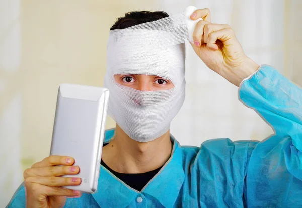 Portret młodego mężczyzny z traumą w jego głowie i elastyczne bandażach wokół jego głowy, trzymając tablet — Zdjęcie stockowe
