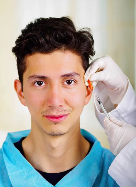 Hombre joven guapo, recibiendo inyecciones de tratamiento cosmético facial, los médicos mano con la jeringa de sujeción de guantes — Foto de Stock