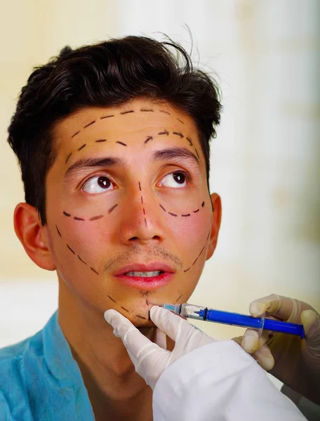Primer plano de un joven guapo, recibiendo inyecciones de tratamiento cosmético facial, manos de los médicos con la jeringa de sujeción de guantes —  Fotos de Stock