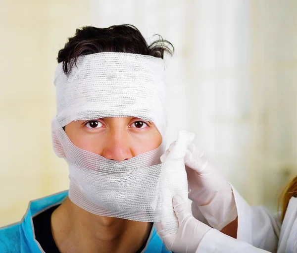 Lekarz dotyka mężczyzn s głowa z traumą w jego głowie i elastyczne bandażach wokół jego głowy — Zdjęcie stockowe