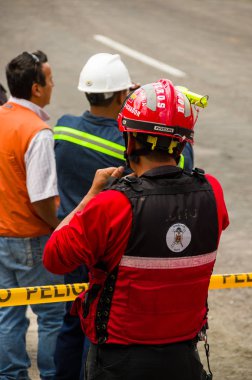 Quito, Ekvator - 09 Aralık 2016: Tehlike teyp sokaklarda arkasında bekleyen itfaiye adam bir Tanımlanamayan grubu