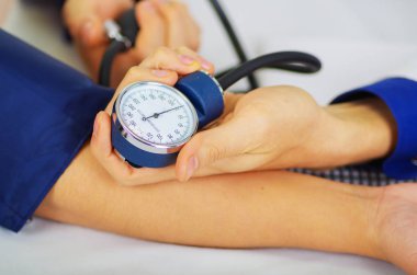 Bir kadın ile bir tensiometer onu kolundan Oda arka plan danışmanlık doktor sırasında darbe duymak steteskop kullanarak genç bir doktorun yakın çekim