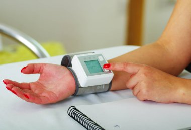 Oda arka plan danışmanlık doktor onu kolundan otomatik bir tensiometer kullanarak bir genç hastanın yakın çekim