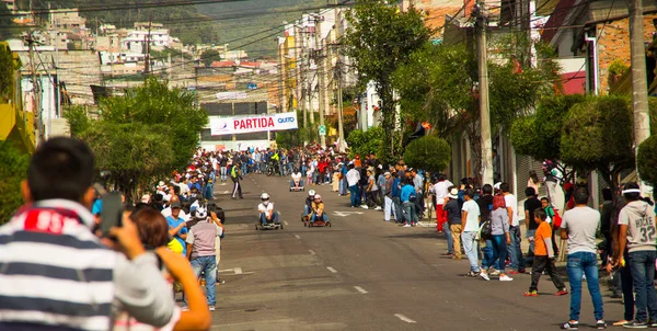 Quito, Ecuador - 06 de mayo de 2017: Un pueblo no identificado observando un coche de carreras de madera en un camino urbano dentro de las calles de la ciudad de Quito — Foto de Stock