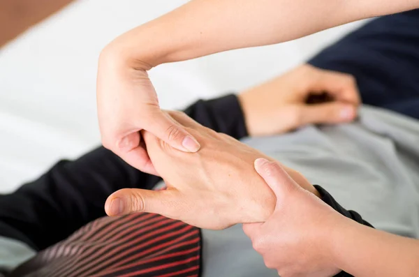 Primer plano de un fisioterapeuta de masaje haciendo masaje de manos de un atleta masculino, en el fondo de consultorio médico — Foto de Stock