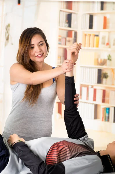 Masaje deportivo. Hermoso masaje terapeuta masajes brazos de un atleta masculino, en un fondo de consultorio médico — Foto de Stock