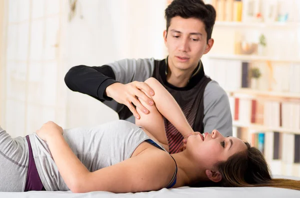 Masaje deportivo. Hnadsome masajista terapeuta de masaje codo de una atleta femenina, en un fondo de consultorio médico — Foto de Stock