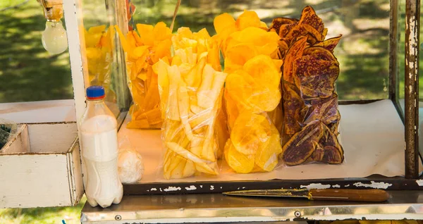 Вкусные ломтики жареного банана, юкки и сладкого картофеля внутри пластикового пакета с бутылкой соли на общественном рынке — стоковое фото