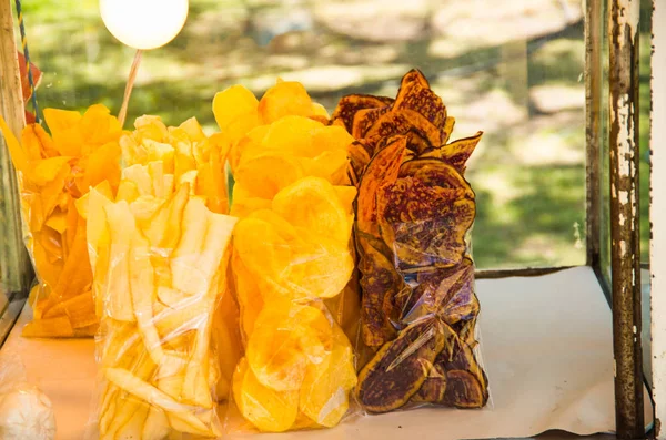 Délicieuses tranches de plantain frit, de yucca et de patate douce à l'intérieur d'un sac en plastique avec une bouteille de sel dans un marché public — Photo