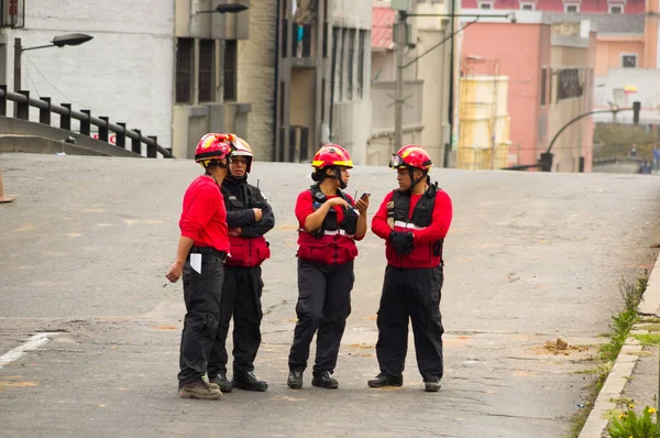 Quito, Ecuador - 09 de diciembre de 2016: Un grupo de bomberos no identificados con equipo, hablando y usando sus teléfonos celulares en las calles — Foto de Stock