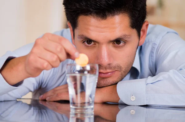 Hombre guapo cayendo tableta efervescente en un vaso de agua —  Fotos de Stock