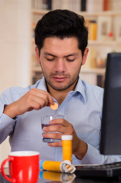 Przystojny mężczyzna opadanie tabletki musującej tabletki w szklance wody — Zdjęcie stockowe