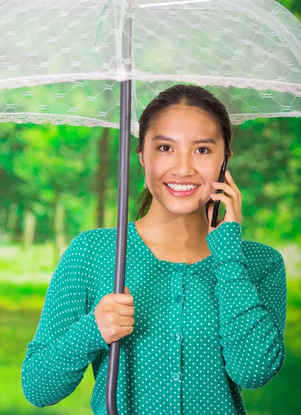 Cep telefonu kullanarak güzel sonbahar parkta, şemsiye ile yeşil kazak giyen genç güzel kadın — Stok fotoğraf