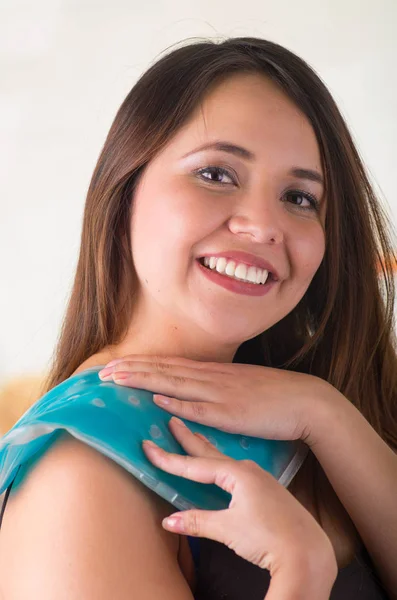 Primer plano de una hermosa mujer sonriente sosteniendo paquete de gel de hielo en su hombro, concepto médico, en el fondo de la oficina — Foto de Stock