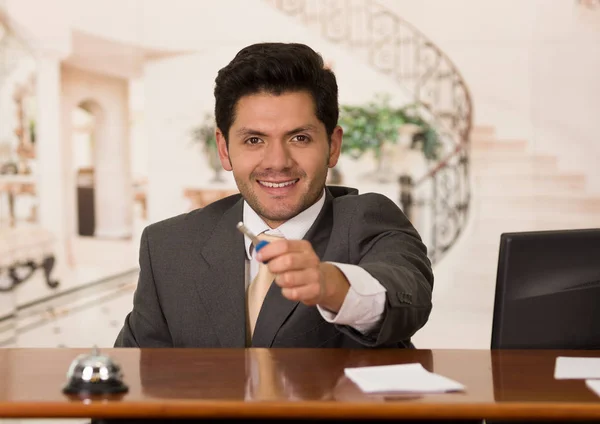 Happy smiling receptionist in hotel giving key to guest, hotel background — Stock Photo, Image