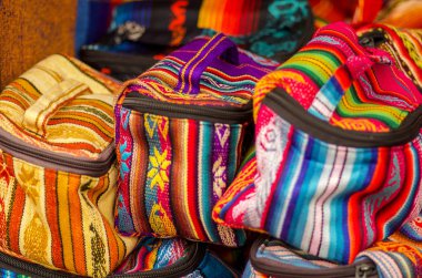 OTAVALO, ECUADOR - MAY 17, 2017: Beautiful andean traditional lunch box textile yarn and woven by hand in wool, colorful fabrics background clipart