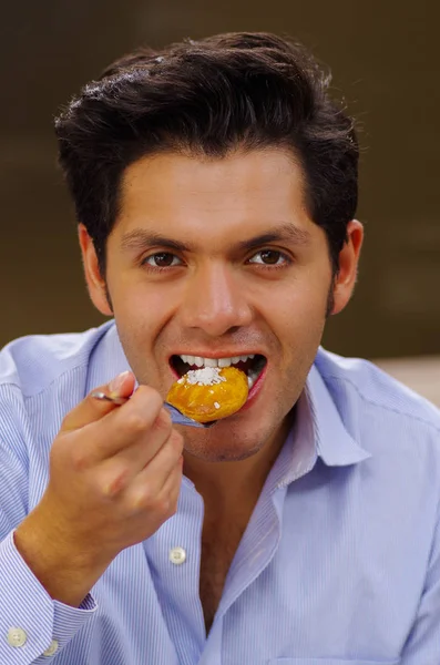 Красивый человек ест вкусный турецкий десерт sekerpare с кокосовым порошком на коричневом фоне — стоковое фото