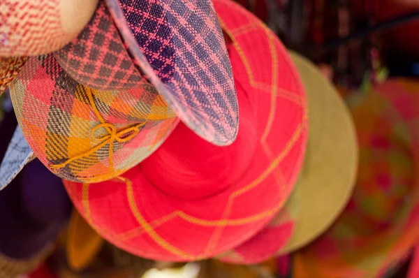 Close-up de uma bela jovem sorridente que se esconde atrás do fio têxtil roupa tradicional andina e tecido à mão em lã, fundo tecidos coloridos — Fotografia de Stock