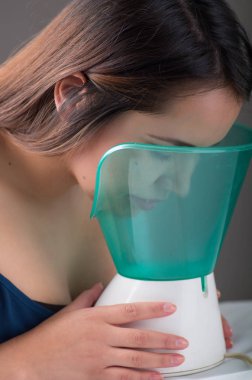 Genç kadının siyah arka plan üzerine bir tıbbi Buharlaştırıcı Nebulizatör makine ile enhalasyon yapması