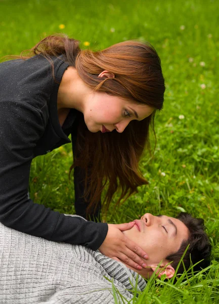 Красивая женщина оказывает первую помощь красивому молодому человеку, сердечно-легочная реанимация, на фоне травы — стоковое фото