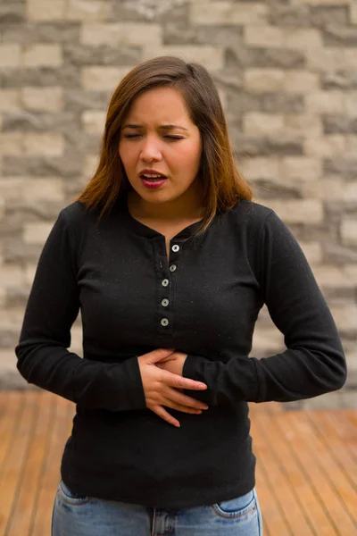 Młoda piękna kobieta złego samopoczucia i dotykając jej żołądka, koncepcja resuscytacji krążeniowo-oddechowej, w niewyraźne tło — Zdjęcie stockowe