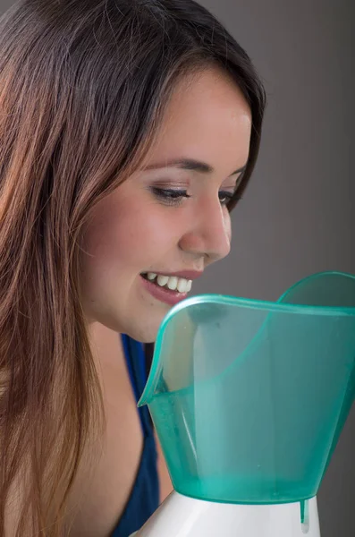 Primer plano de una mujer joven inhalando con un nebulizador vaporizador sobre fondo gris —  Fotos de Stock