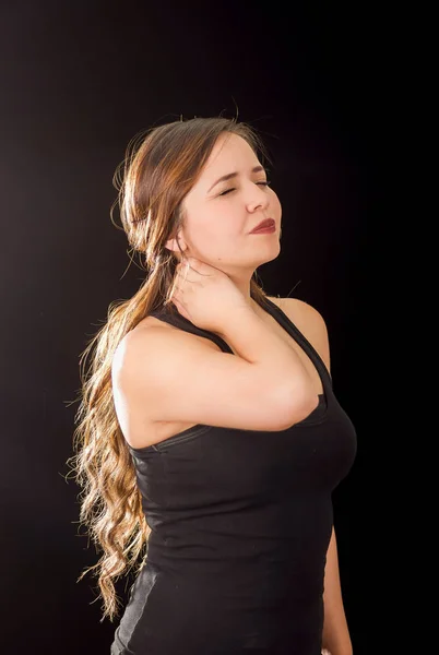 Mooie jonge dame lijden crick na training in een zwarte achtergrond — Stockfoto