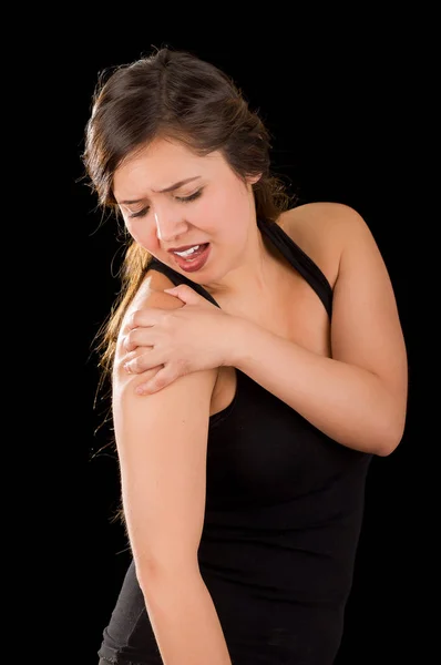 Beautiful young woman suffer from shoulder pain in a black background — Stock Photo, Image
