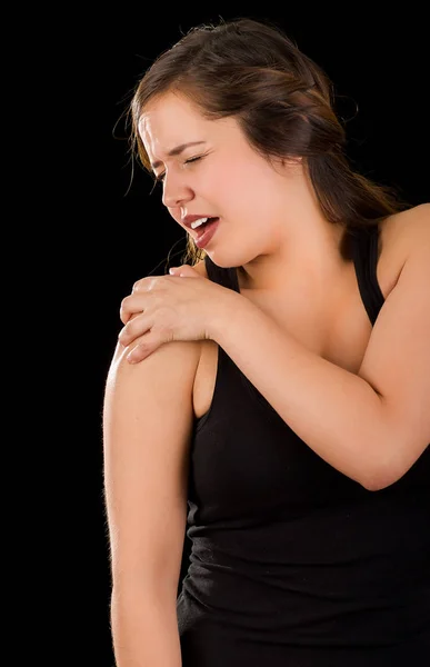 Schöne junge Frau leidet unter Schulterschmerzen vor schwarzem Hintergrund — Stockfoto