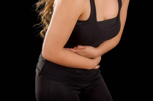 Hermosa mujer joven con dolor de estómago o náuseas en un fondo negro —  Fotos de Stock