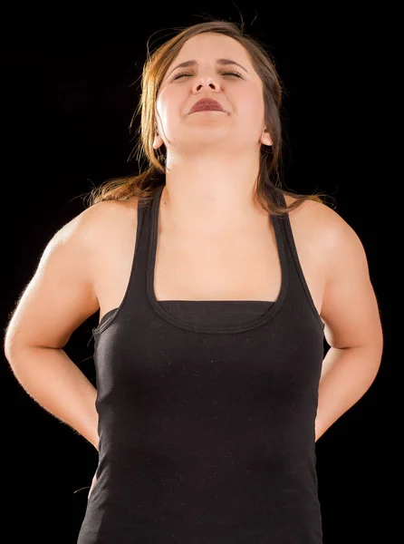 Young beautiful sportwoman suffer cervical pain in her lower back, in black background — Stock Photo, Image