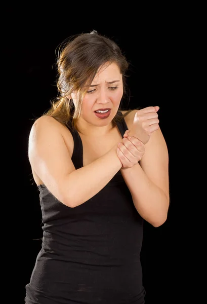 Schöne Frau mit schmerzhaftem Handgelenk vor schwarzem Hintergrund — Stockfoto