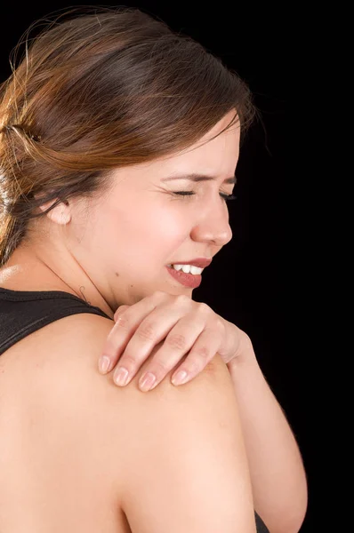 Close up of a beautiful young woman suffer from shoulder pain in a black background — Stock Photo, Image