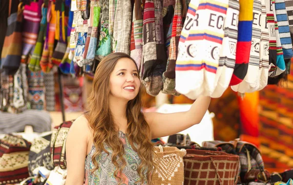 Mulher bonita segurando uma bolsa tradicional andina roupas têxteis fios e tecidos à mão em lã, fundo tecidos coloridos — Fotografia de Stock