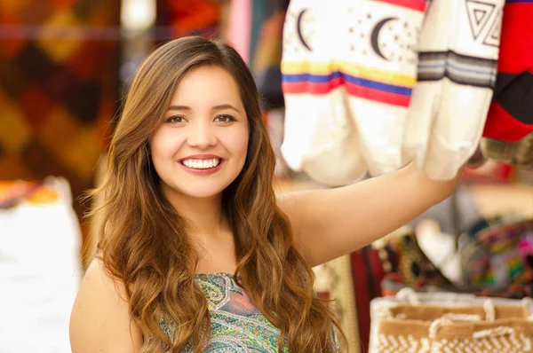 Close-up de uma mulher bonita segurando uma bolsa tradicional andina roupas têxteis fios e tecidos à mão em lã, fundo tecidos coloridos — Fotografia de Stock